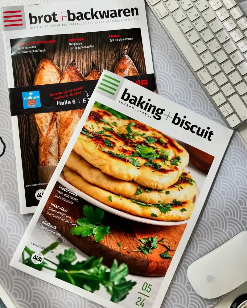 Cover of Baking+Biscuit International magazine featuring a stack of freshly baked flatbreads, garnished with parsley, showcasing traditional and modern bakery innovations.